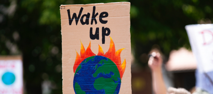 A protester holding a sign of a burning earth saying 'wake up'.
