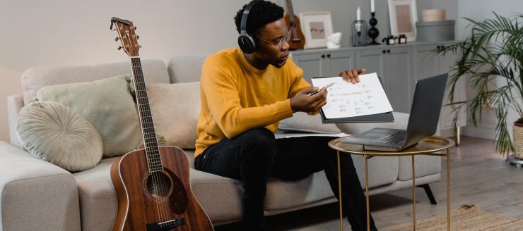 man teaching music theory online with guitar next to him